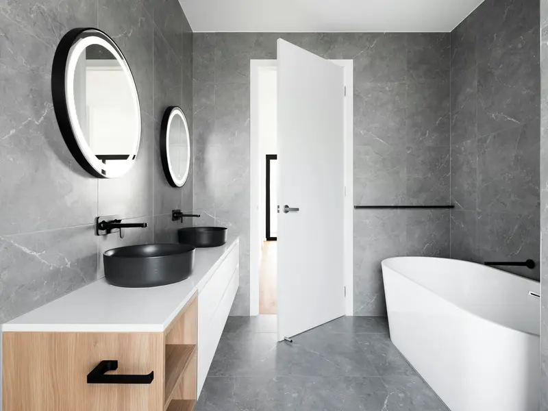 Modern saniertes Badezimmer mit grauen Fliesen und freistehender Wanne